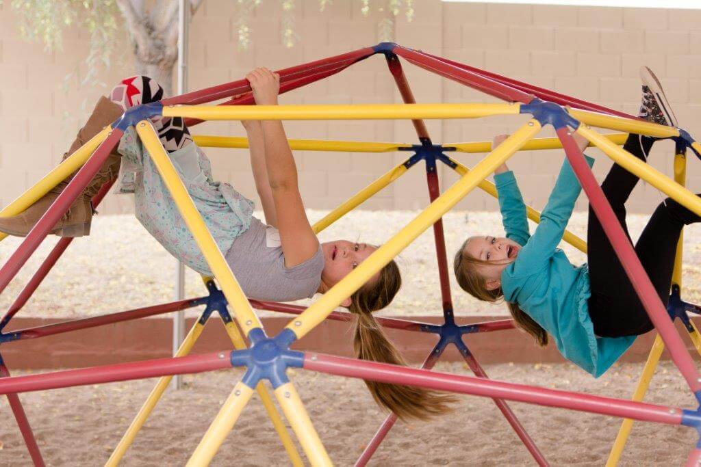 Children hanging from domed playground equipment.